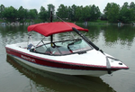 A red and white MasterCraft boat floating on a lake with a black bow sling secured to the bow.